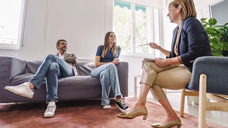 couple sitting on a couch together in a couples therapy session with their therapist
