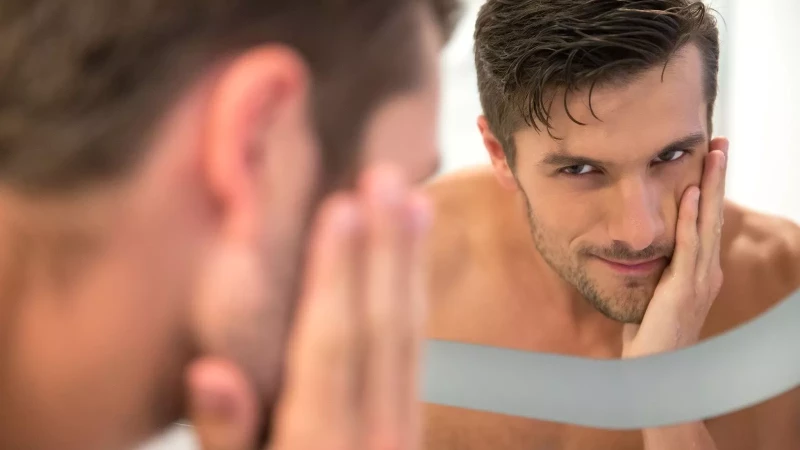 man smirking as he looks in the mirror
