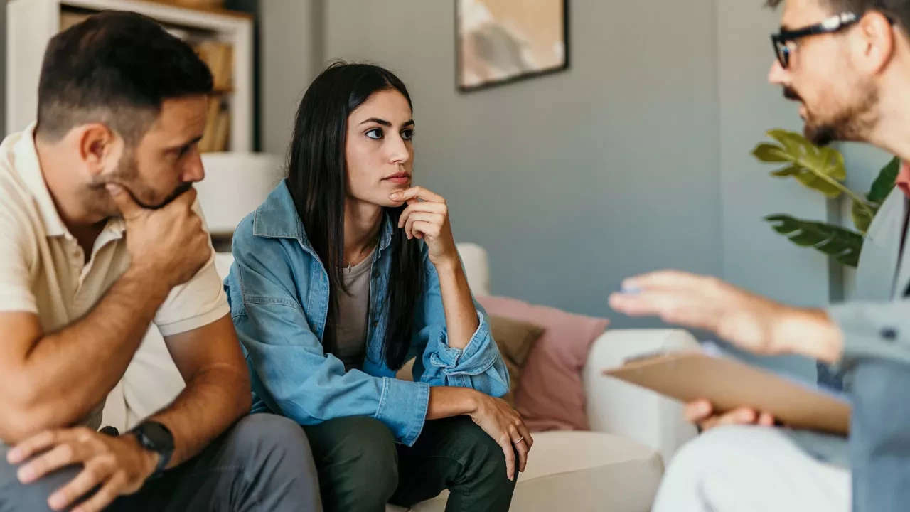 Couple talking to a therapist sitting on a couch