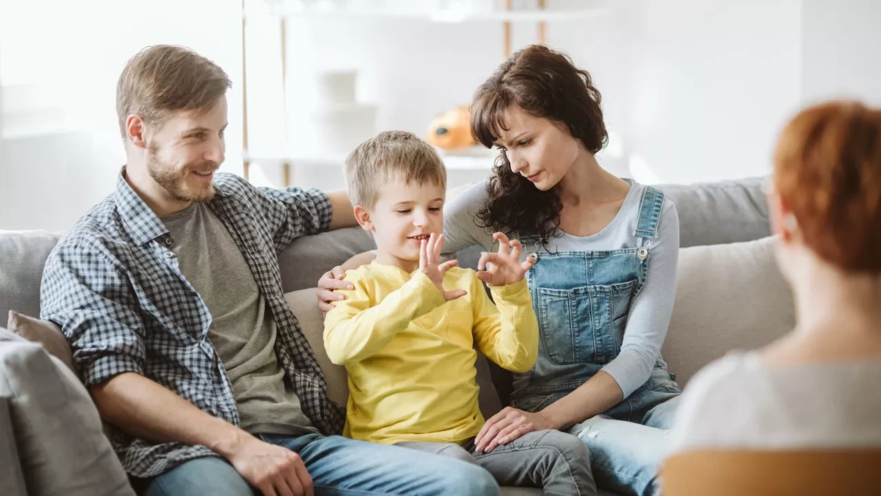 a mom and dad with their child on a couch talking to a therapist