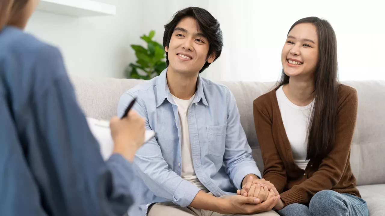 Young couple holding hands sitting together