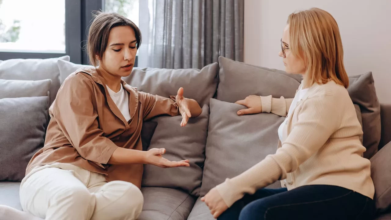 Young woman sitting on a couch talking to a therapist