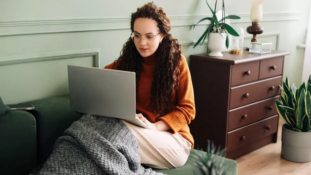 Relaxed young woman sitting on sofa using a laptop