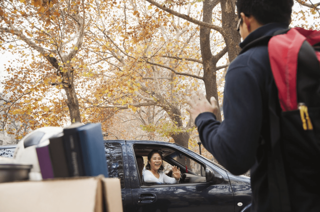 college student waving goodbye to mom in the car